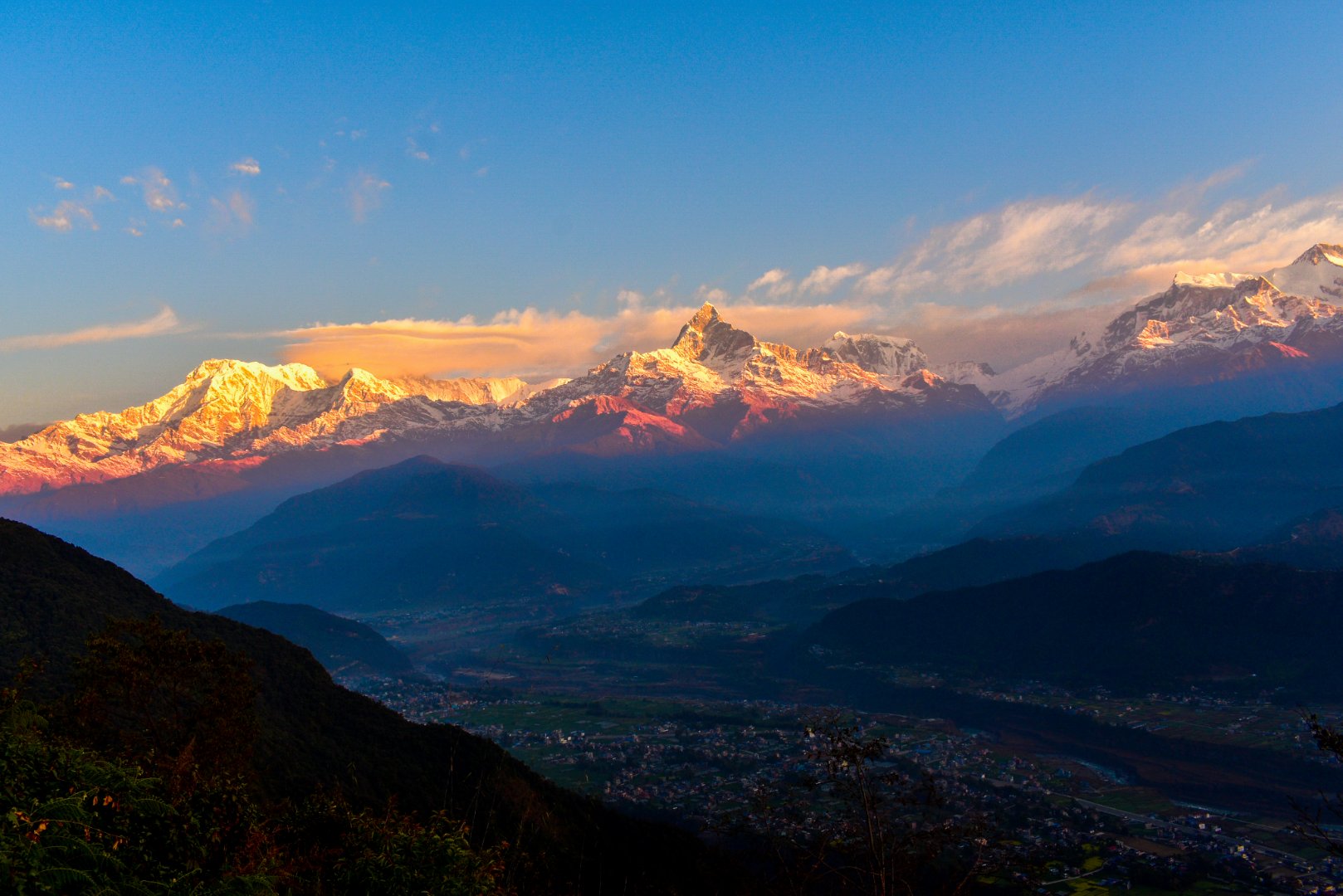 Orange sunrise light hitting the snow-covered Annapurna peaks as seen from Sarangkot viewpoint