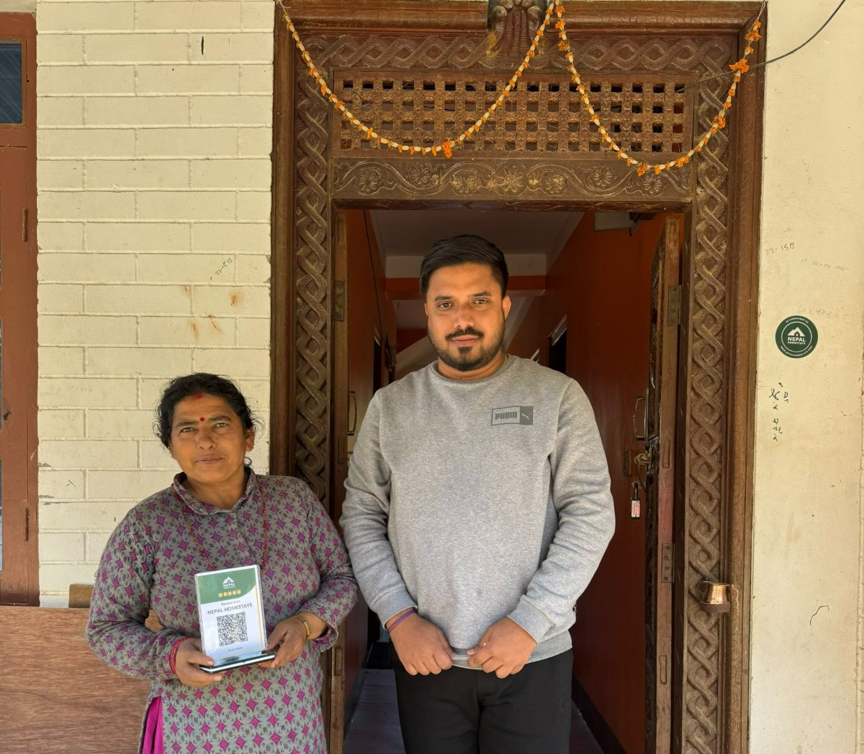 A host at Balthali Community Homestay holds her Nepal Homestays QR code, her first direct link to travelers from around the world.