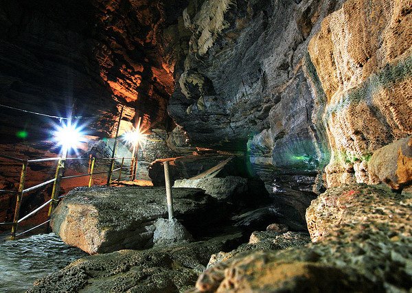 Inside Mahendra Cave with natural rock formations lit by dim lights