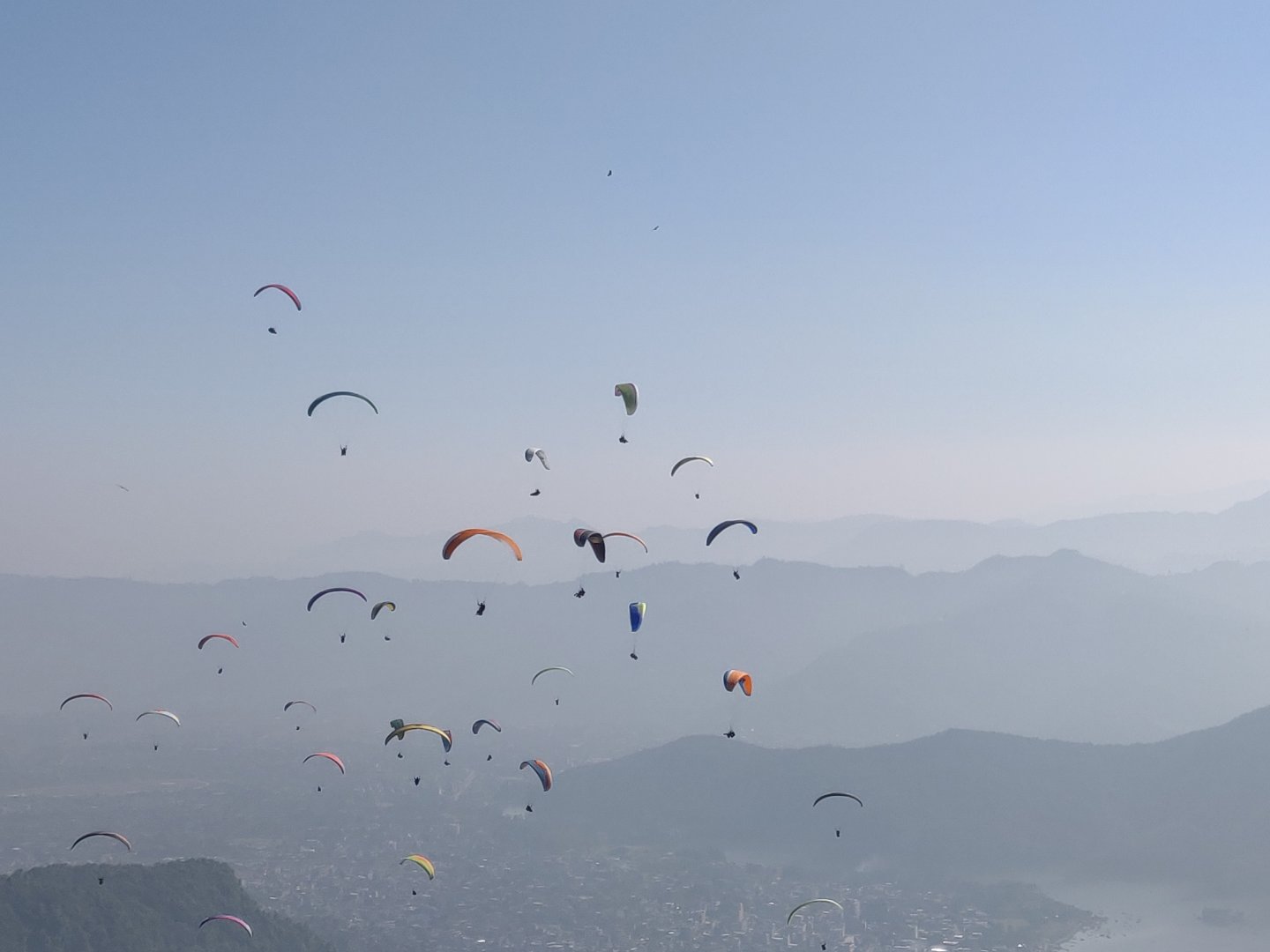 Paragliding over Pokhara with Phewa Lake and green hills visible below