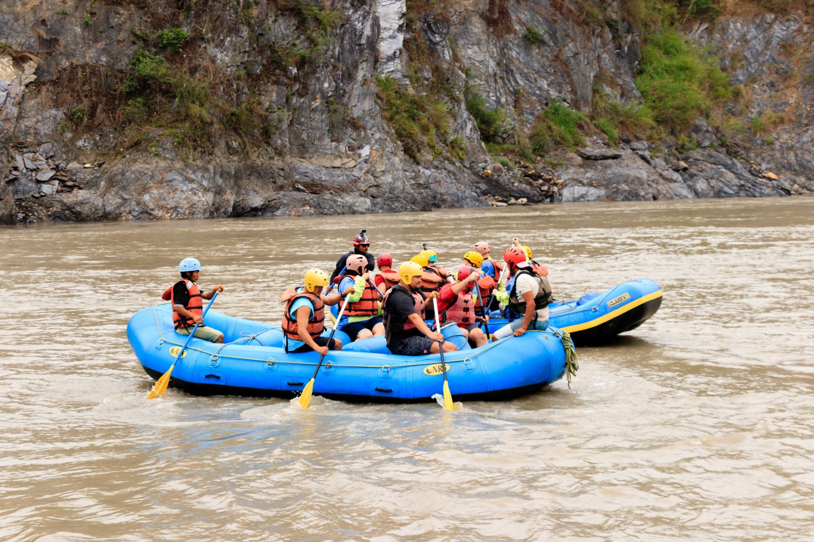 People in helmets and life jackets rafting through white water rapids on a river near Pokhara