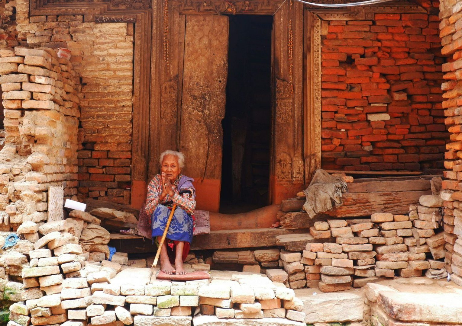 Elderly woman seated at her doorway.