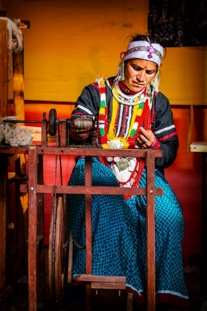 Woman spinning thread on a wooden wheel.